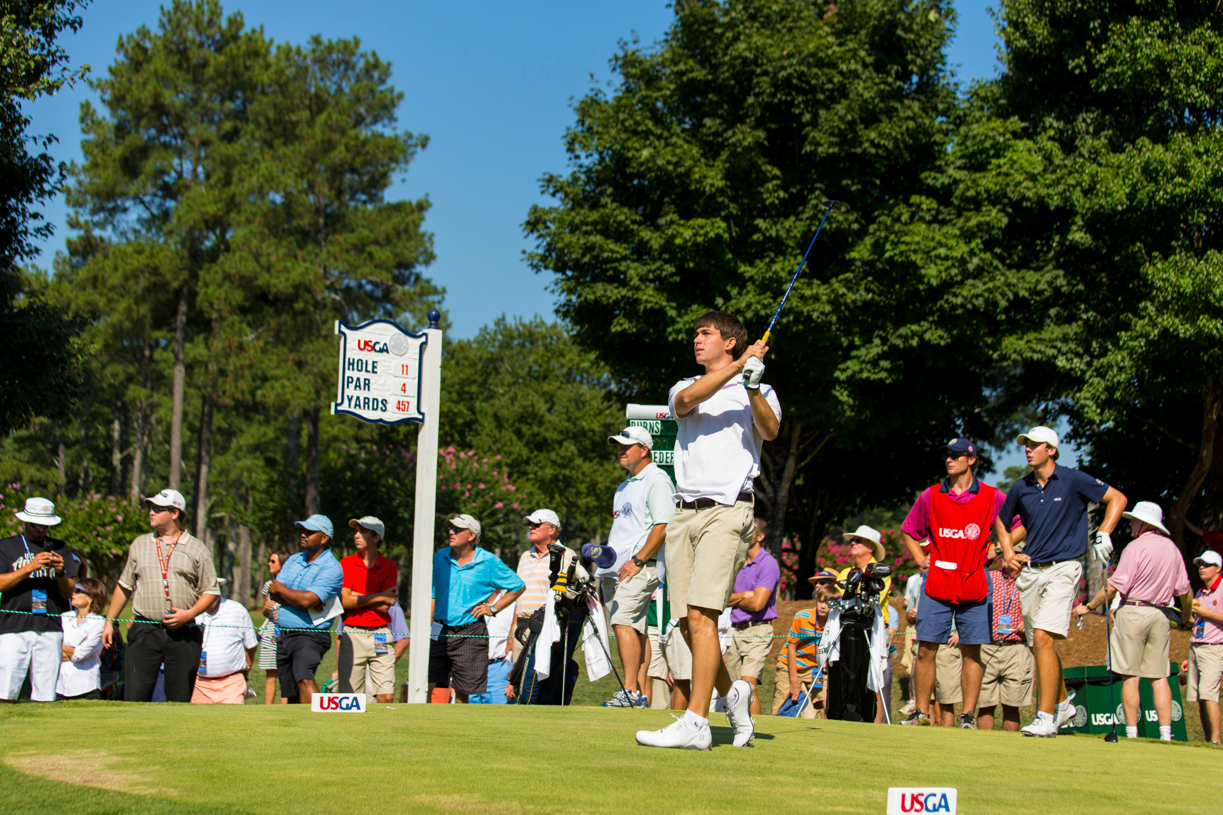Ollie Schniederjans watches his tee shot on the 11th hole during the second round of match play at the 2014 U.S. Amateur at Atlanta Athletic Club in Johns Creek, Ga. on Thursday, Aug. 14, 2014. (Copyright USGA/John Mummert)