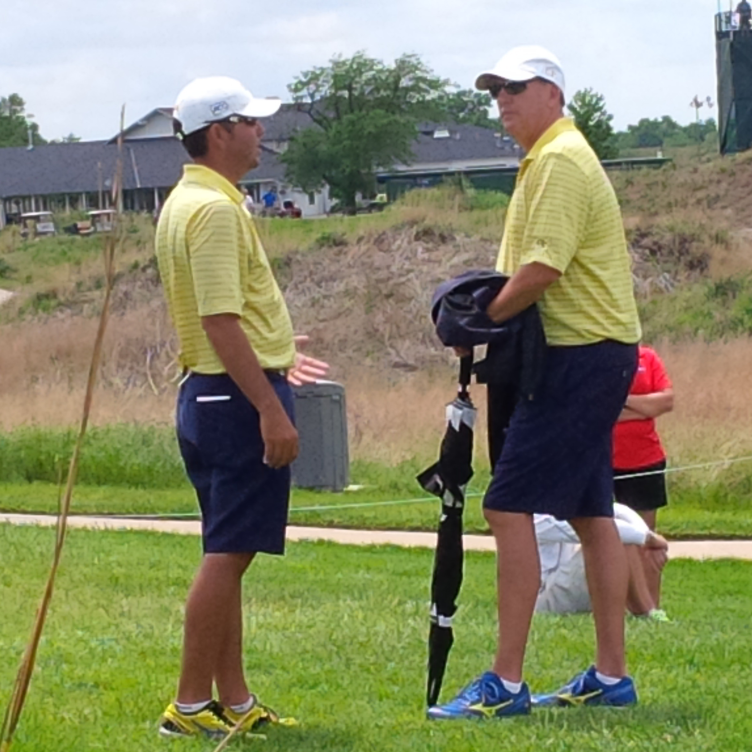 Assistant coach Brennan Webb and head coach Bruce Heppler chat by the 17th tee while play is backed up Saturday at the NCAA Championship in Hutchinson, Kan.
