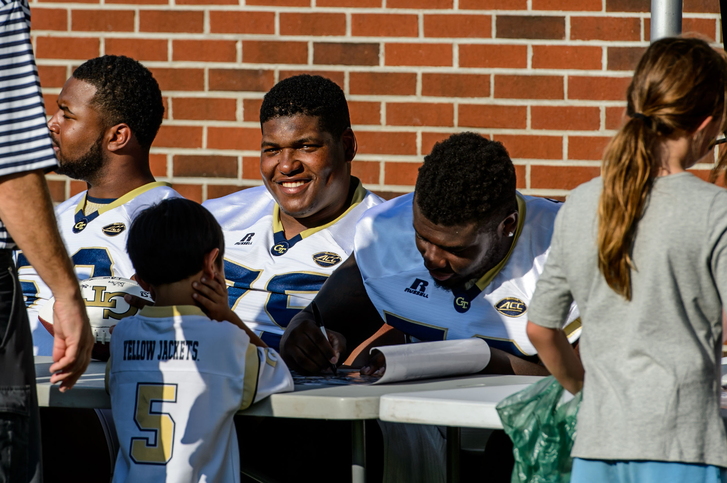Freddie Burden (58) signs an autograph as Errin Joe (75) smiles