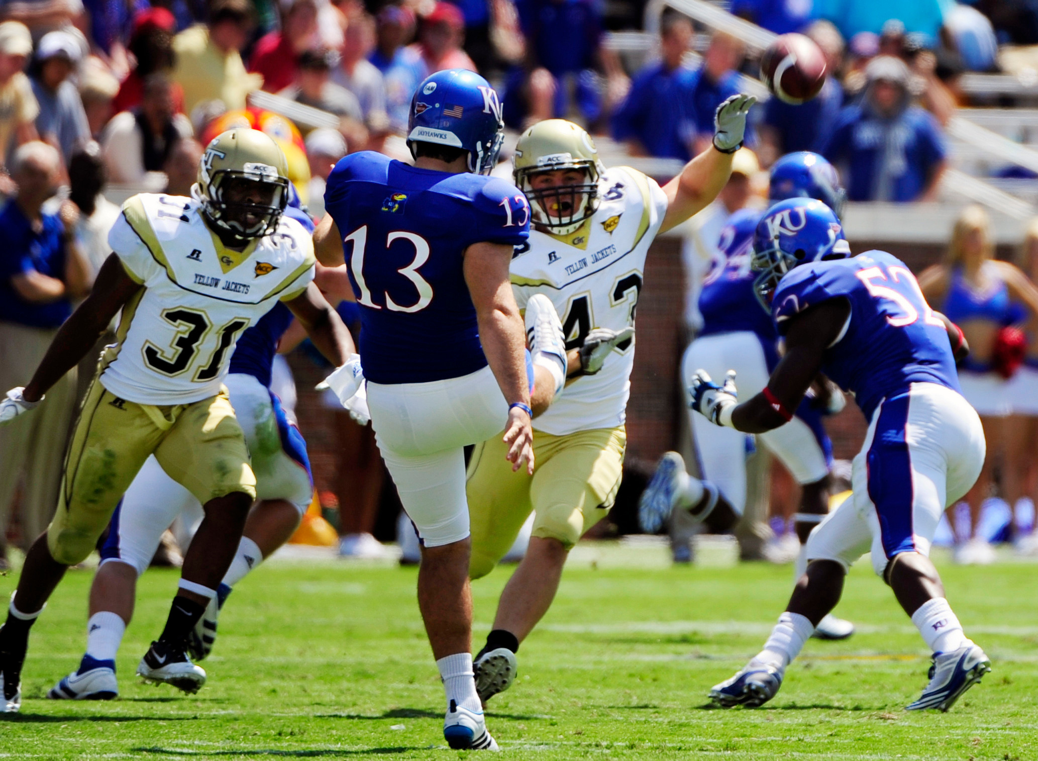 Kansas kicker Ron Doherty (13) punts the ball away under pressure from Georgia Tech's Denis Onwuala (31) and Kyle Travis (43) during the first half of an NCAA college football game at Bobby Dodd Stadium in Atlanta on Saturday, Sept. 17, 2011. (AP Photo/David Tulis)
