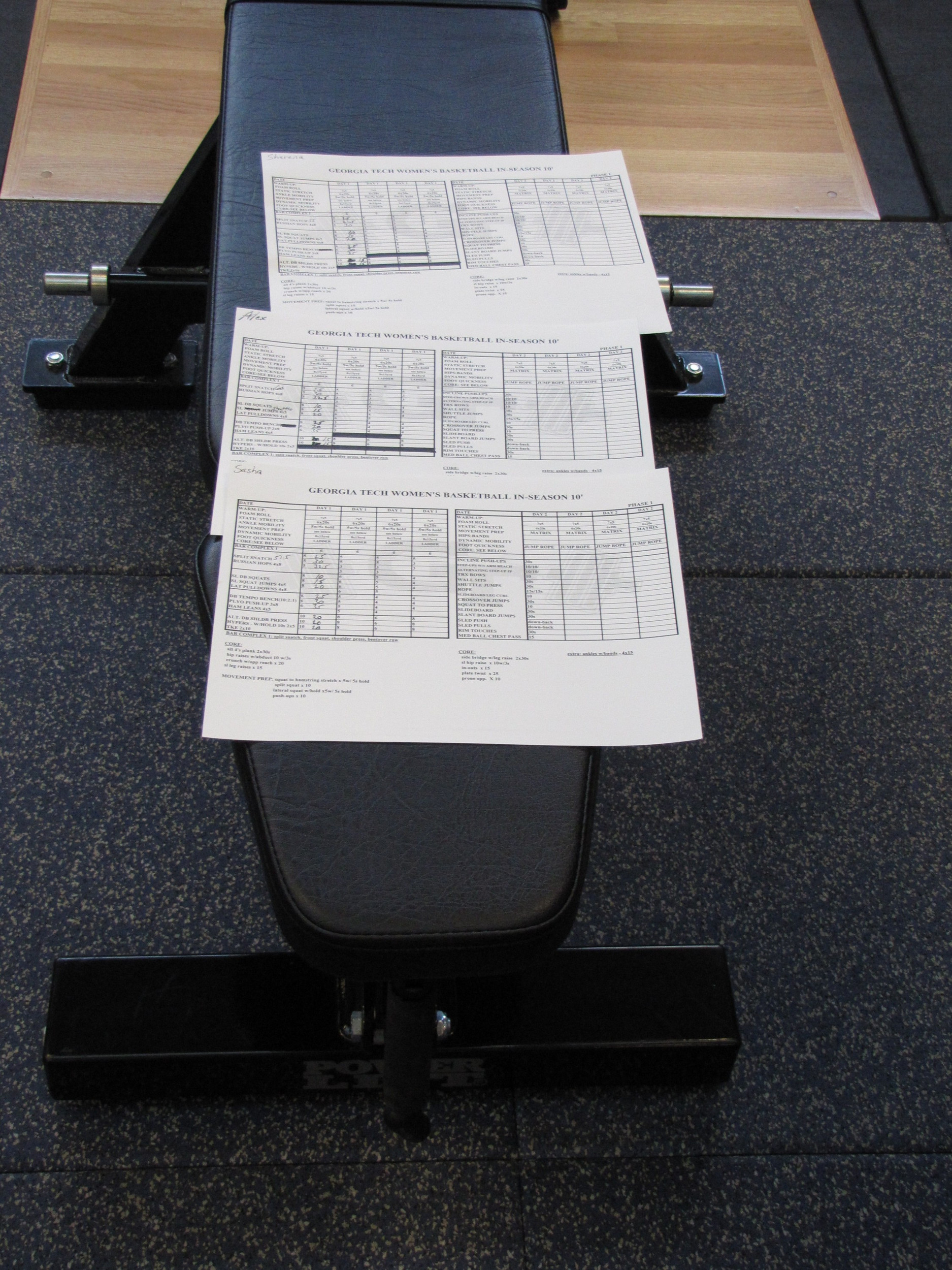 The team lays out their workout sheets on a bench