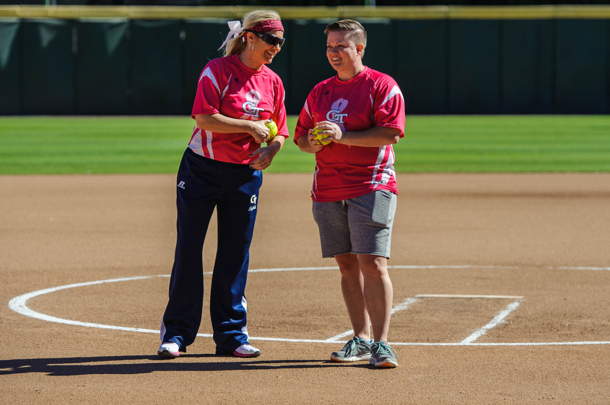 Coach Shelly Hoerner hands the ball to former Yellow Jacket and breast cancer survivor, Amy Hosier.