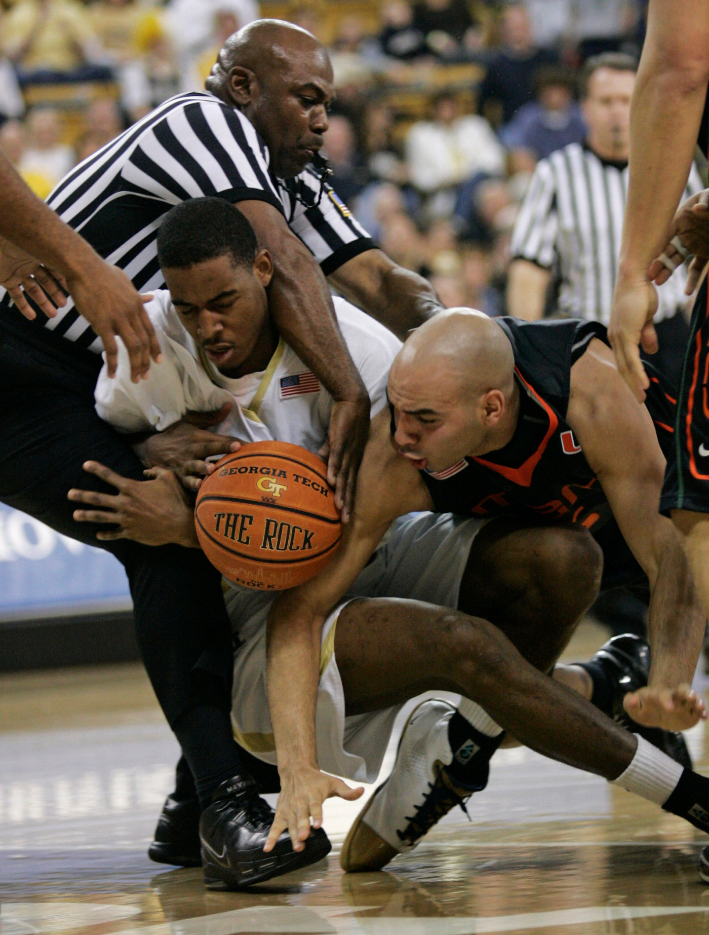 Referee Les Jones, left, gets tangled up with Georgia Techs' Alade Aminu and Miami guard Eddie Rios, right, as they fight for the ball during the first half of a basketball game Sunday, Feb. 17, 2008, in Atlanta. (AP Photo/John Amis)