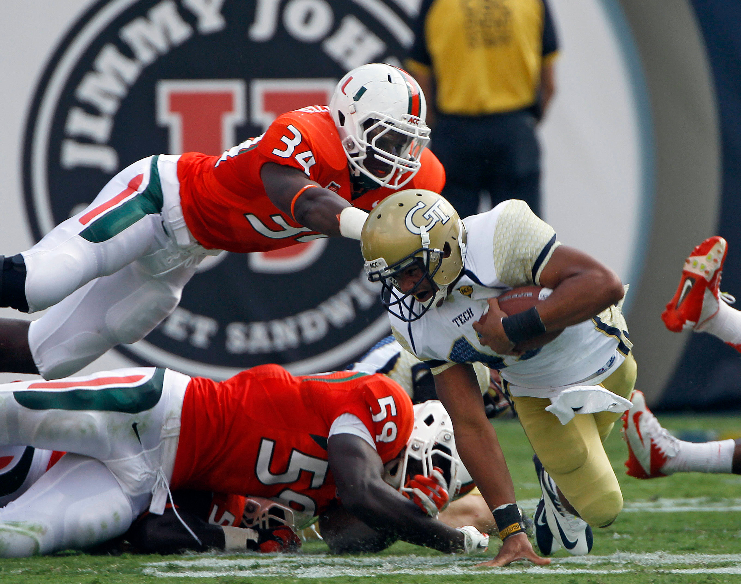 Georgia Tech quarterback Tevin Washington (13) is stopped by Miami linebacker Jimmy Gaines (59) and linebacker Thurston Armbrister (34) in the first half of an NCAA college football game in Atlanta on Saturday, Sept. 22, 2012. (AP Photo/John Bazemore)