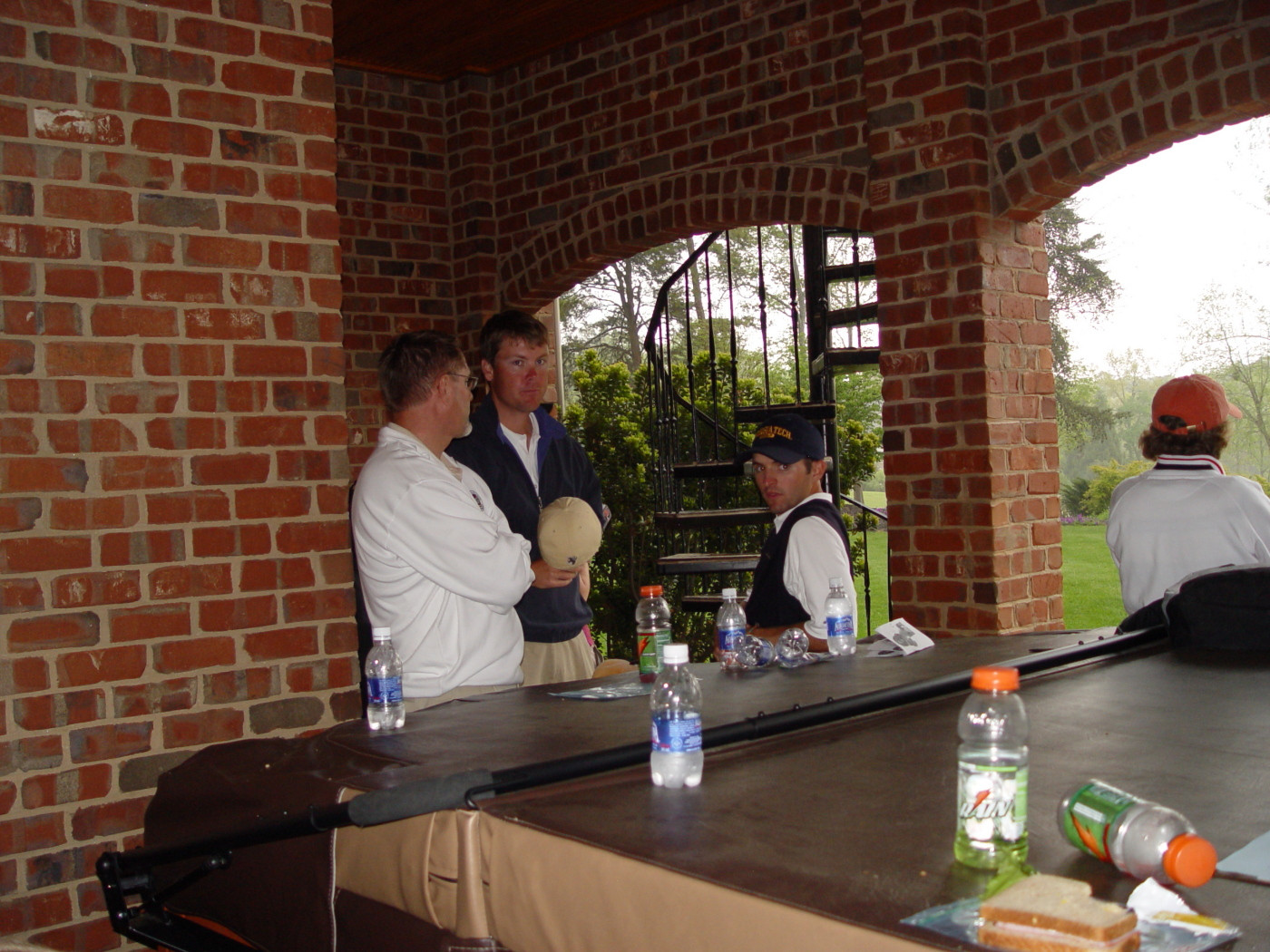 Doug Dragoo, assistant coach Christian Newton and David Dragoo wait out the rain delay under the back porch of a home adjacent to the 14th tee during the final round of the ACC Golf Championship, April 20, 2008.
