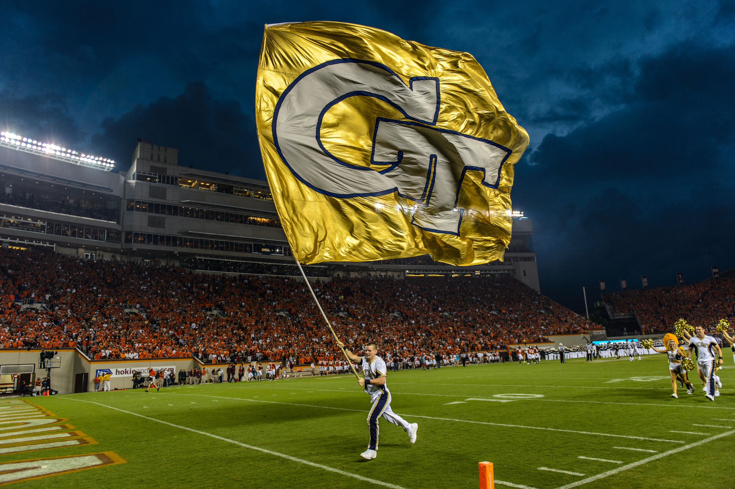 Georgia Tech Cheerleader running with the GT Flag before kickoff