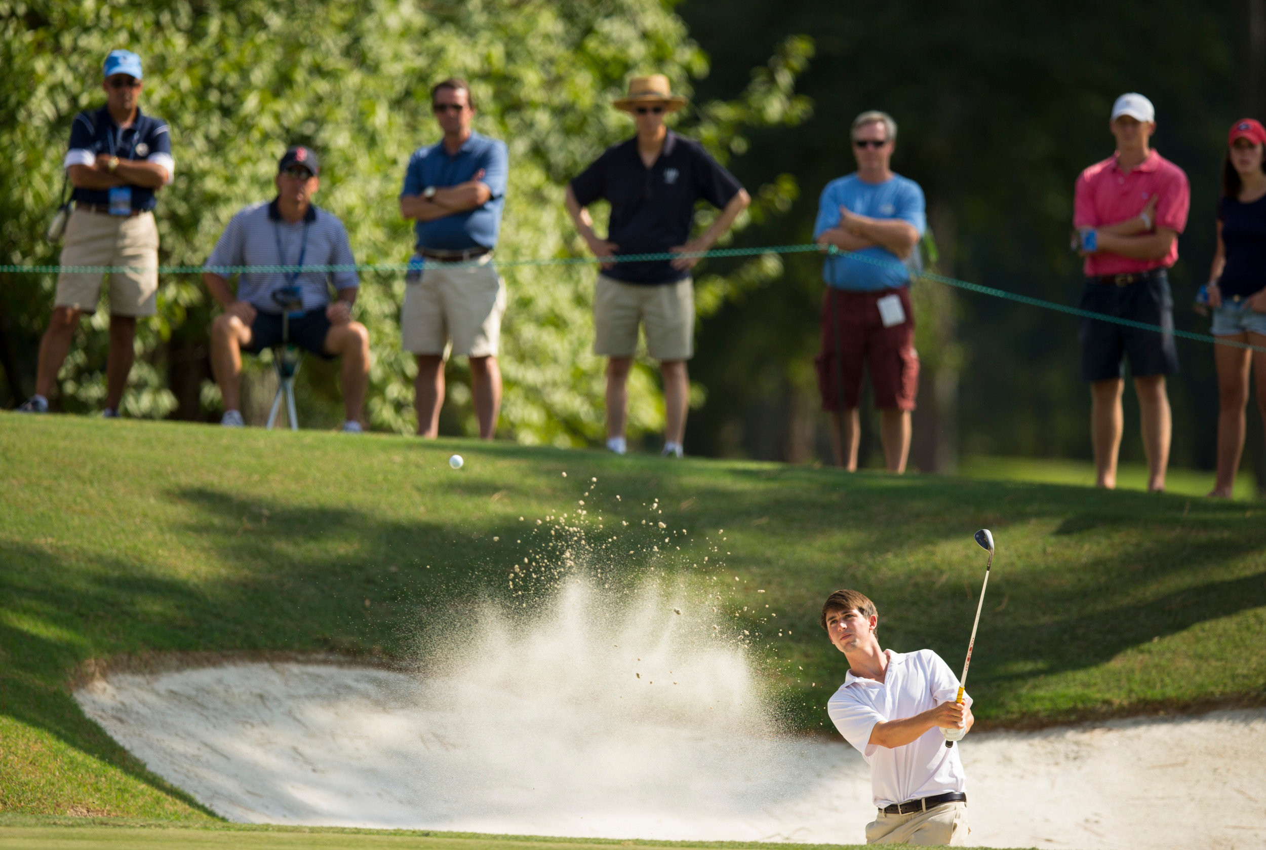 Ollie Schniederjans blasts out of a greenside bunker on the 15th hole during the third round of match play at the 2014 U.S. Amateur at Atlanta Athletic Club in Johns Creek, Ga. on Thursday, Aug. 14, 2014. (Copyright USGA/John Mummert)