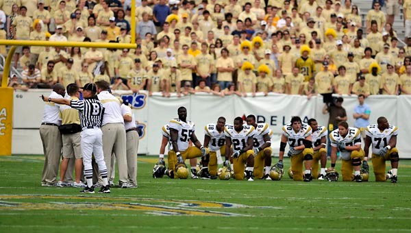 Georgia Tech players take a knee while Sedric Griffin is attended to by trainers. (Photo by LensEffects)