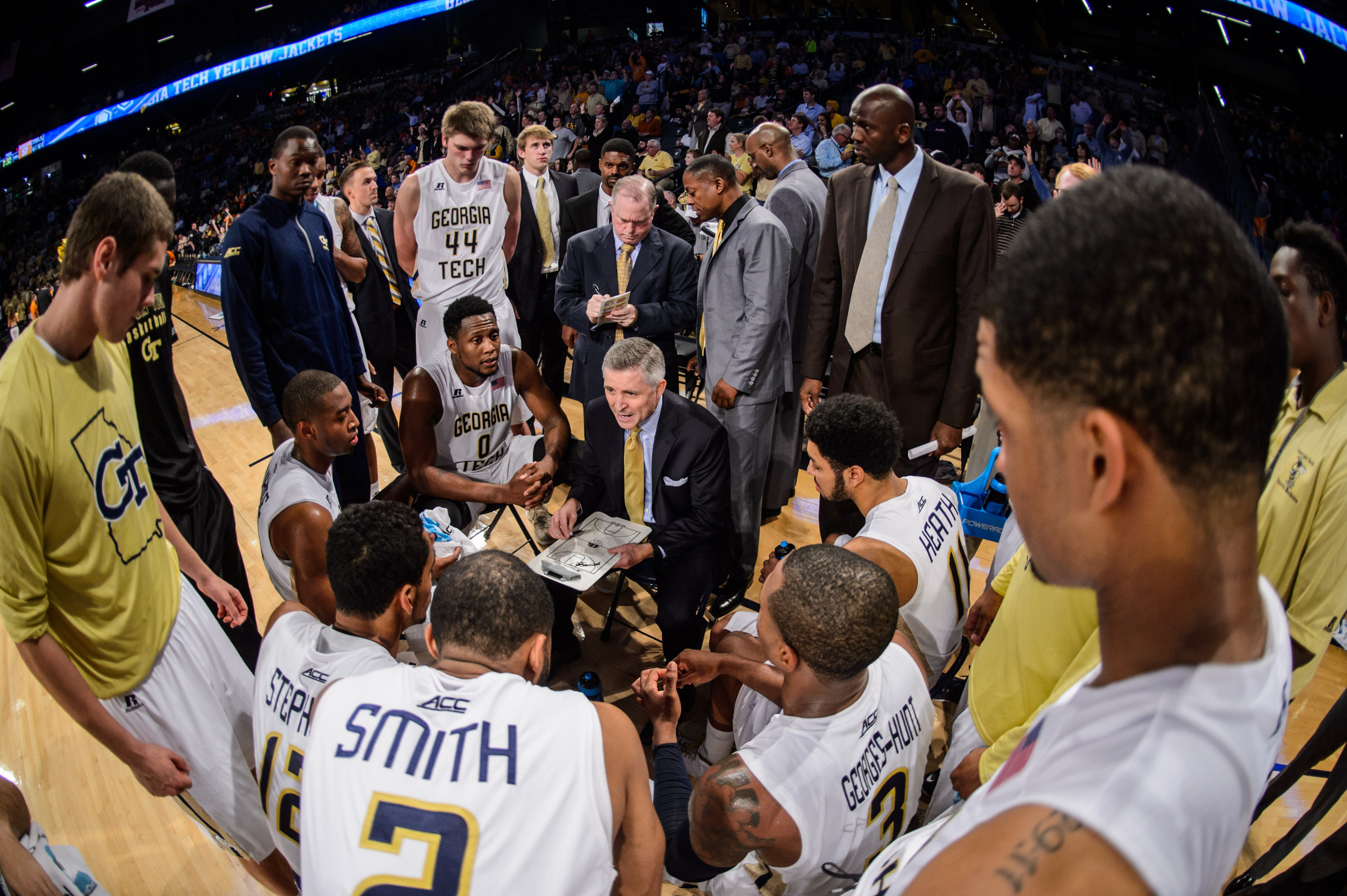 Coach Brian Gregory strategizes with the team during a timeout